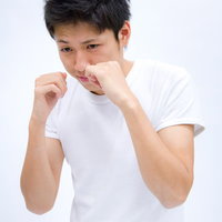 白い背景の前で構えてシャドーボクシングする男性の写真