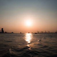 夕陽のオレンジの光が水面に反射して光る水辺の風景の写真