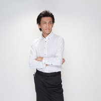 黒いベストに白いシャツで腕を組むバーテンダーの男性の写真