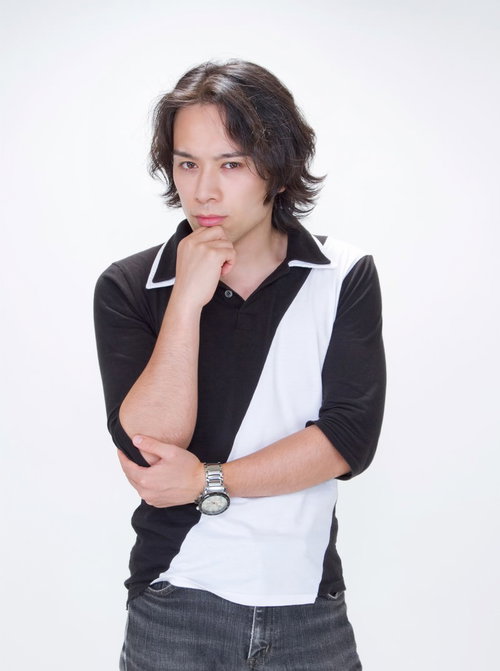 水色の壁の前で腕を組み眉をひそめて考え込む男性