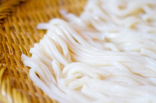 ざるの上につやつやした麺が盛られたざるうどんの接写