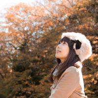 黄色く色づいた秋の木を背景にロシア帽をかぶった女性の写真