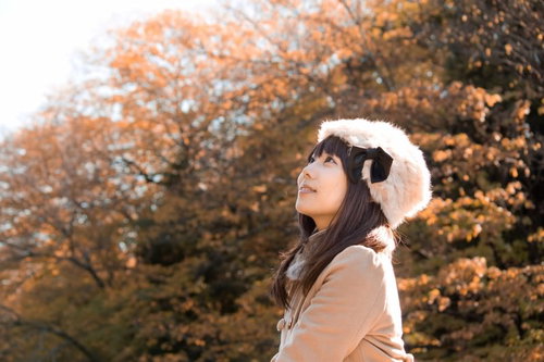 黄色く色づいた秋の木を背景にロシア帽をかぶった女性