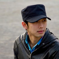 つばの広い帽子を目深にかぶってポーズする男性の写真