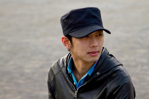 つばの広い帽子を目深にかぶってポーズする男性