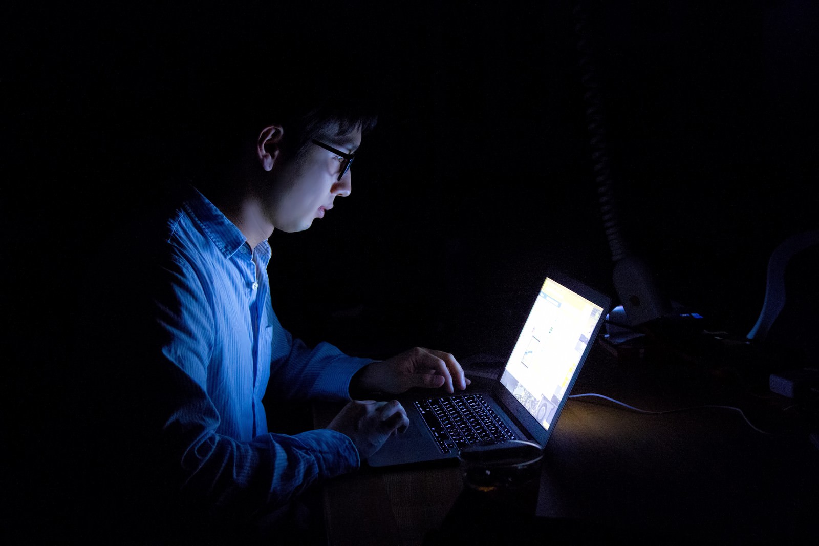 暗闘でPC画面に照らされる残業の男性［モデル：大川竜弥］