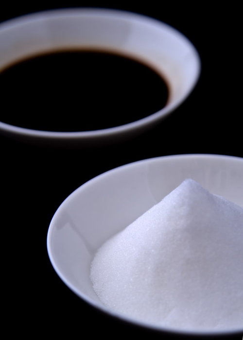 白い小皿に盛られた三角形の盛塩と隣に置かれた醤油差し