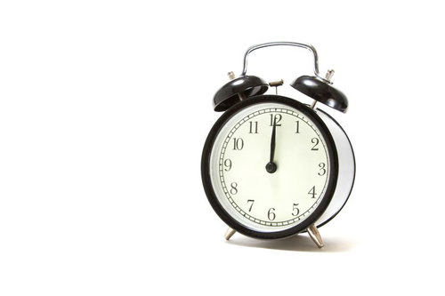 短い針が12を指すお昼の時間の丸い目覚まし時計