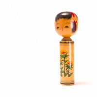 丸い頭と赤い模様が描かれた木製のこけしの置物の写真