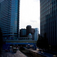 夕方のオレンジの空を背景にビルが並ぶ都会のオフィス街の写真