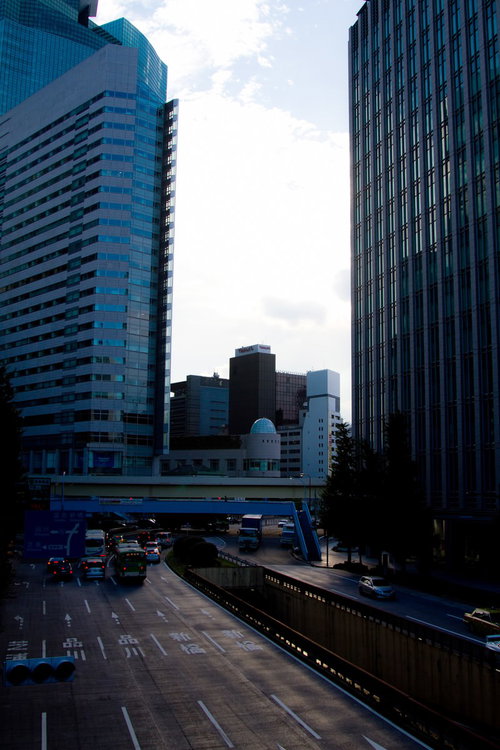 夕方のオレンジの空を背景にビルが並ぶ都会のオフィス街