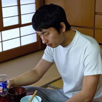 食卓でお酒のグラスを持ったままうなだれる男性の写真
