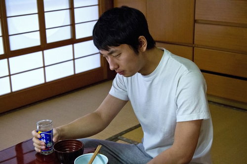 食卓でお酒のグラスを持ったままうなだれる男性