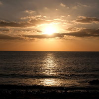 水平線に太陽が沈みオレンジに染まる屋久島の海と夕焼けの写真