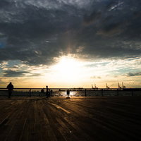夕陽のオレンジの空を背景に自転車に乗る少年のシルエットの写真