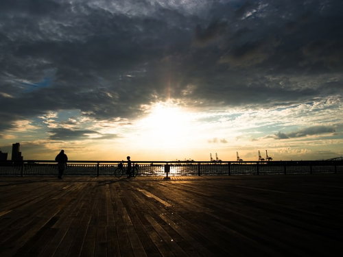 夕陽のオレンジの空を背景に自転車に乗る少年のシルエット