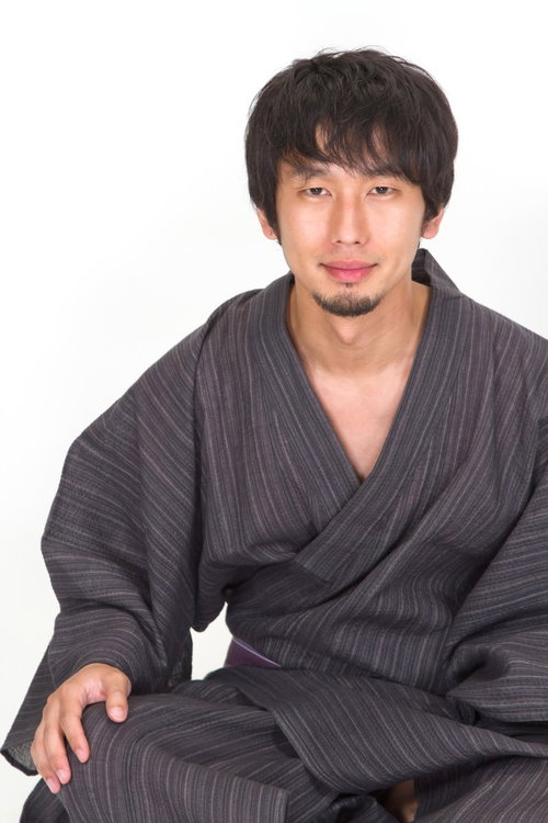 白い背景の前で胡坐をかいてこちらを見る甚平姿の男性