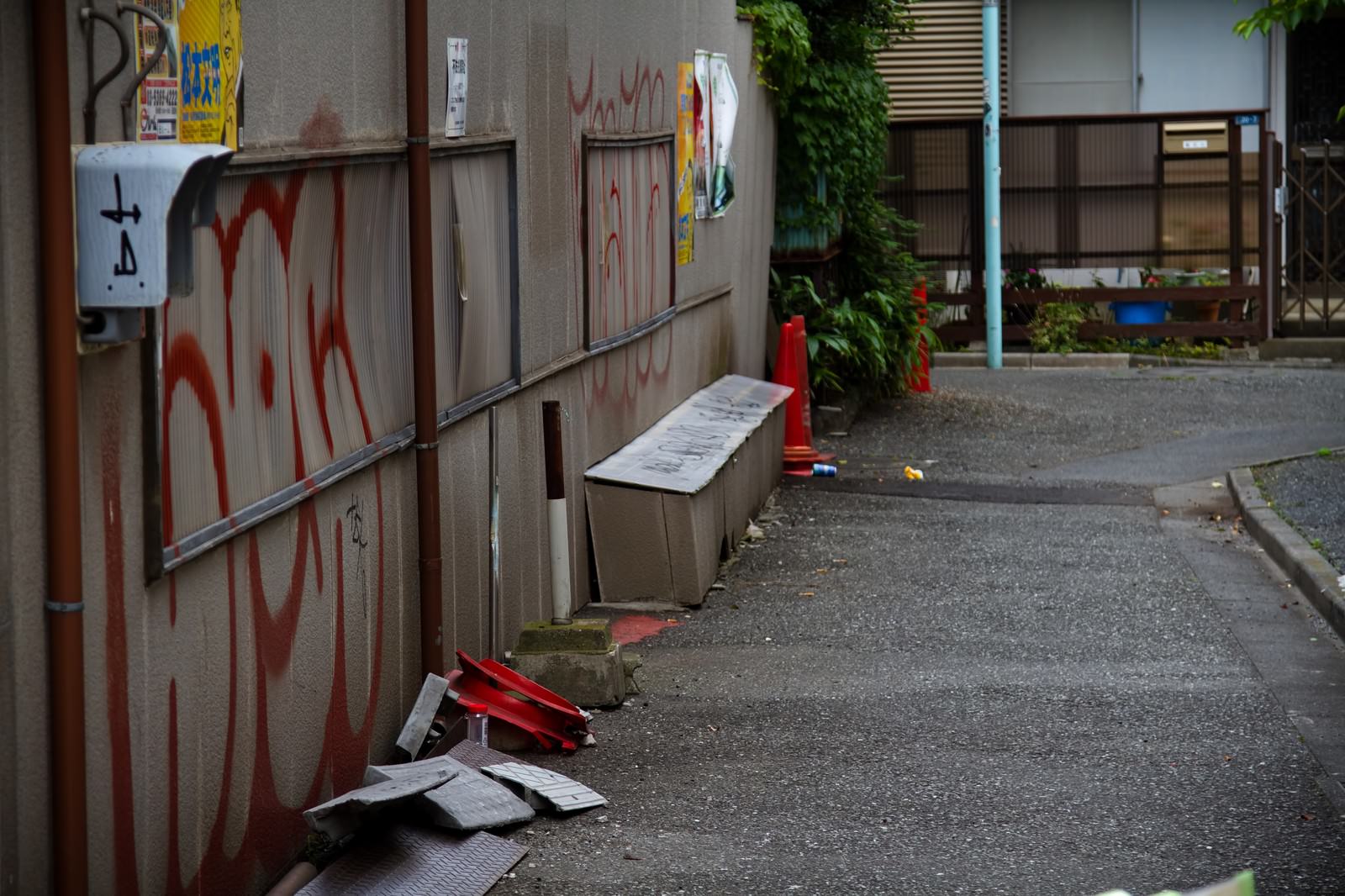 赤い落書きと三角コーンが置かれた路地裏