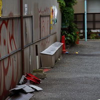 赤い落書きと三角コーンが置かれた路地裏の写真