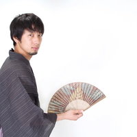 扇子を持ちこちらを見る浴衣男子のポーズの写真
