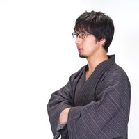 浴衣の袖に手を入れ横を向くメガネの男性の写真