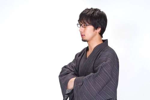 浴衣の袖に手を入れ横を向くメガネの男性