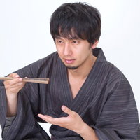 扇子を使って何かを食べる浴衣男子のポーズの写真