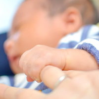 生まれたばかりの赤ちゃんが母親の人差し指をぎゅっと握る手の写真