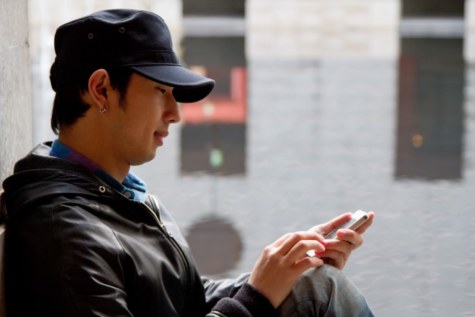 帽子をかぶってスマホを触る男性［モデル：大川竜弥］