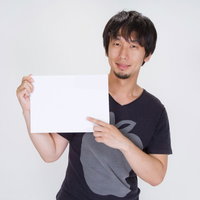 「ご案内」の白いボードを正面に持つ笑顔の男性の写真