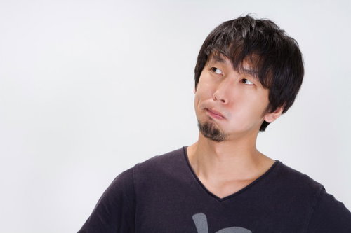 眉間にしわを寄せて不満そうにしかめっ面をする男性