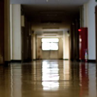 窓から薄い光が差す人気のない廃校の薄暗い校舎の廊下の写真