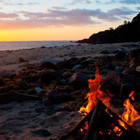 波打ち際の砂浜に炎が上がる屋久島の浜辺の焚き火の写真