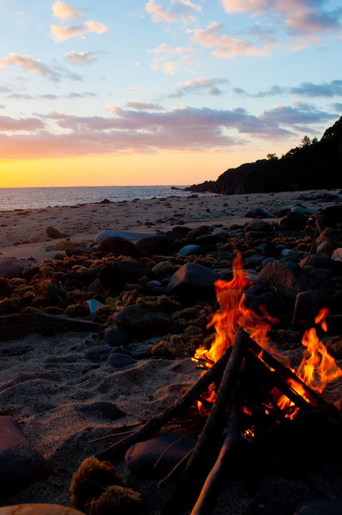 波打ち際の砂浜に炎が上がる屋久島の浜辺の焚き火