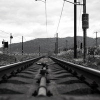 まっすぐ奥へ続く灰色のレールと枕木の線路の写真