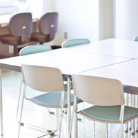 灰色のパイプ椅子と長机が並ぶ会議室や教室の風景の写真