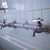 タイル壁に蛇口が並ぶ廃校の手洗い場の写真