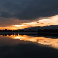 夕焼けのオレンジの空と光が反射して光る水面の風景の写真