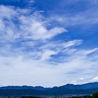遠くに連なるアルプスの山並みと広い青空の写真