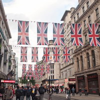 ユニオンジャックが並ぶピカデリーの町並みと人々の写真