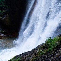 岩肌を白く流れ落ちるしぶきをあげる滝の写真