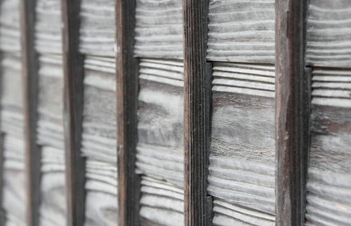 自然光が差し込む縦に並んだ溝模様の木の板塀
