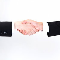 スーツ姿で固く握手を交わすビジネスマンの手元の接写の写真