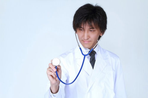 患者の胸に聴診器を当てて診察する医師