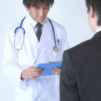 眉間にしわを寄せてカルテを確認する担当医の写真