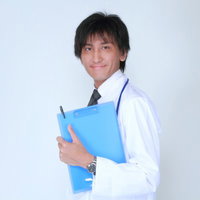 クリップボードのカルテを胸の前に持つ白衣の担当医の写真