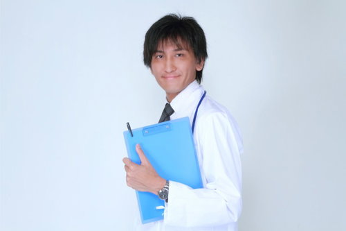 クリップボードのカルテを胸の前に持つ白衣の担当医