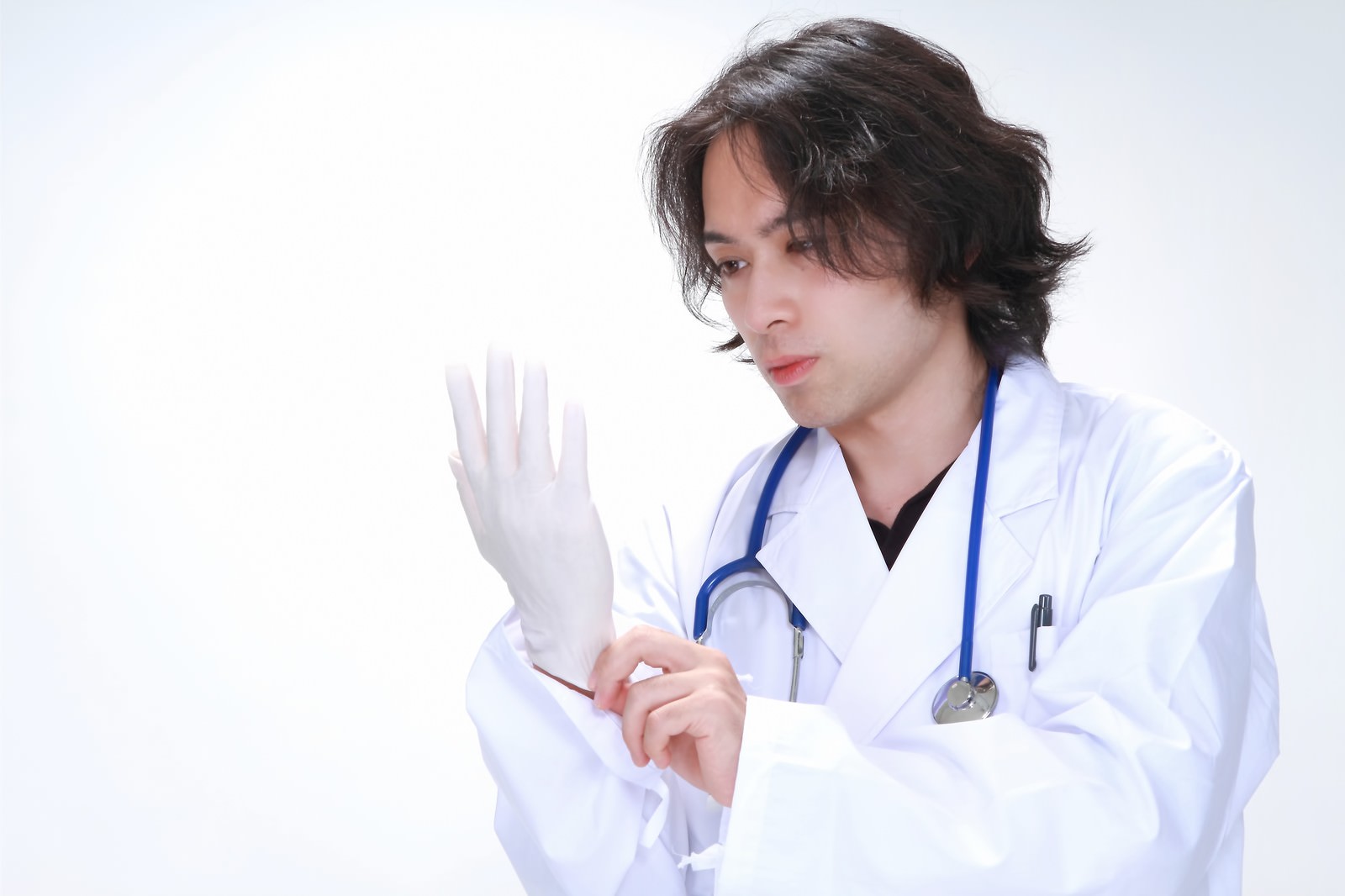 ゴム手袋をはめる若い医師［モデル：マイケルリュー］