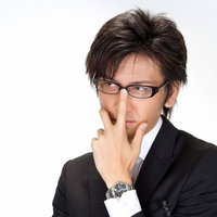 水色の壁の前で眼鏡のフレームに手を当てるビジネスマンの写真