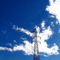 白い雲と夏の青空を背景にそびえる送電鉄塔の写真